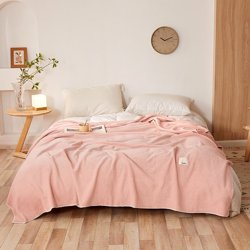 Manta de veludo waffle cor rosa numa cama