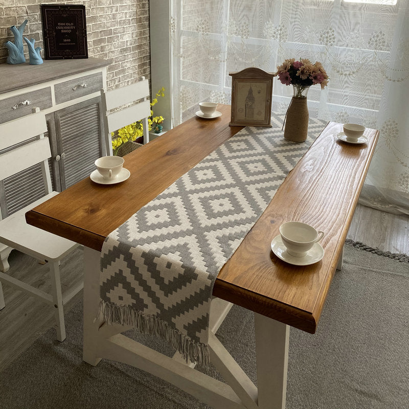 Soothera Table Runner — passadeira tecida com losangos cinza numa mesa de madeira